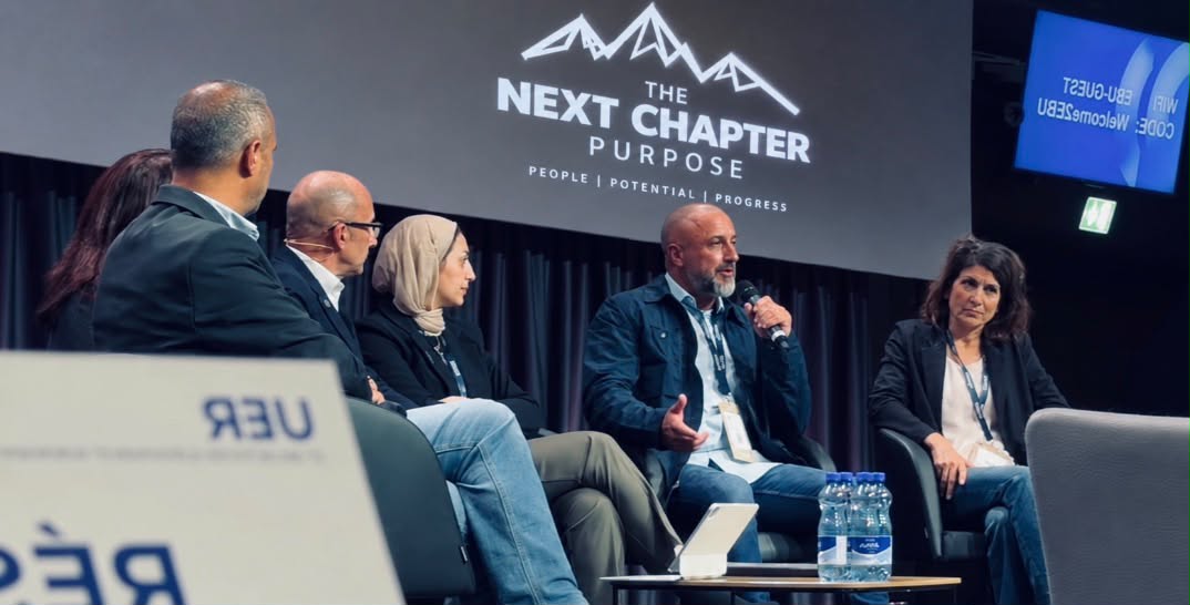 Steve speaking on a panel beneath The Next Chapter logo